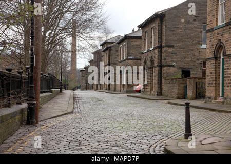 Eine gepflasterte Straße führt zu mehreren Straßen von zurück zu Reihenhaus zurück Häuser im viktorianischen Modell Dorf Saltaire Yorkshire Stockfoto