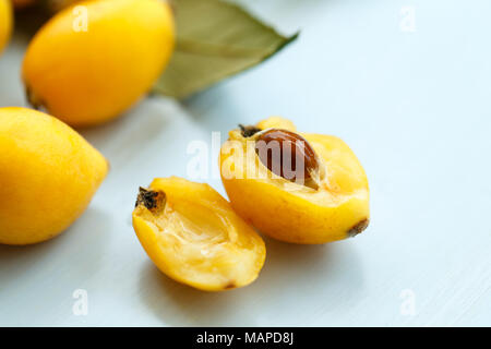 Mispel orange Früchte auf Ast mit Blätter auf einem blauen Hintergrund aus Holz Stockfoto