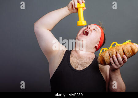 Lustiger Kerl in Sportkleidung essen kleine Hanteln Stockfoto