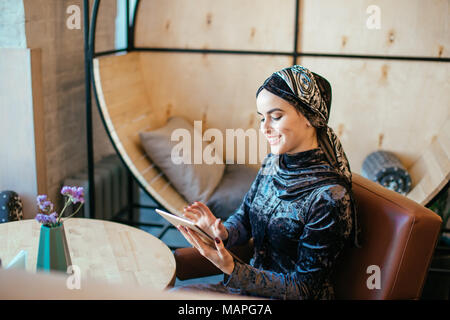 Schöne arabisch muslimischen Mädchen mit Tablette im Cafe Stockfoto