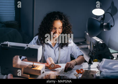 Schneiderin ist threading Perlen vor nähen Maschine in schwarz Zimmer Stockfoto