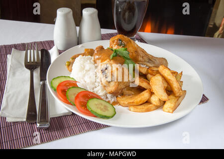 Ein englisches Pub/Restaurant Platte von Huhn und gekochtem Reis mit Chips/Pommes und Englisch chip shop Curry Sauce. Stockfoto