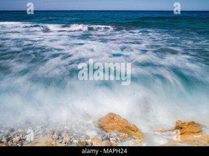 Kreta, bunte Wellen im Meer am felsigen Ufer im östlichen Teil der Insel. Durch die Bewegung des Wassers verwischt. Stockfoto