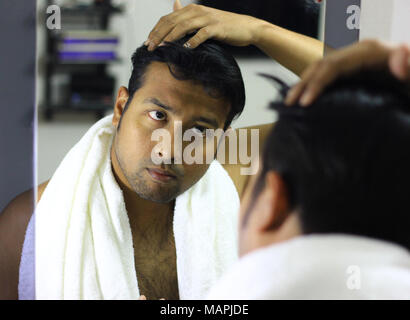 Indische asiatischer Mann auf der Suche nach seinem Auftritt vor einem Spiegel Beauty Styling Lifestyle. Hair Styling Stockfoto