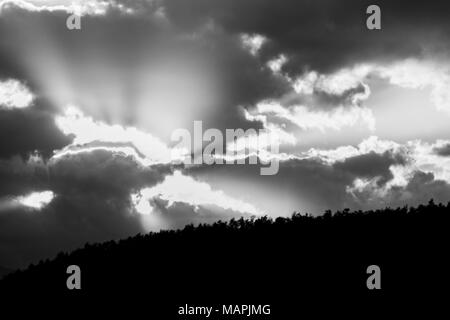 Sonnenuntergang über einem Tal, mit Sonnenstrahlen, die sich durch einige Wolken Stockfoto