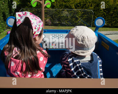 Zwei Kinder Fahrt auf Daddy Schweine auto Fahrt am Solitärspiele Welt, Paultons Park, Hampshire Stockfoto