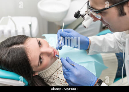 Zahnarzt untersucht den Patienten Zähne mit Hilfe der Brille mit einem Mikroskop Stockfoto