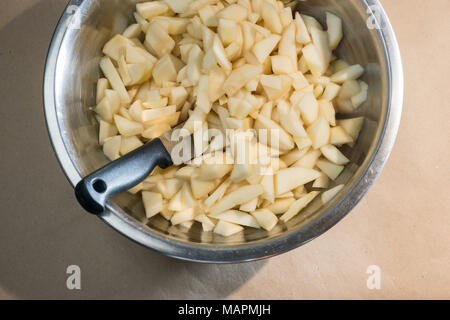 Gehackt geschälte Birnen und ein Messer in einer Metallschüssel Stockfoto