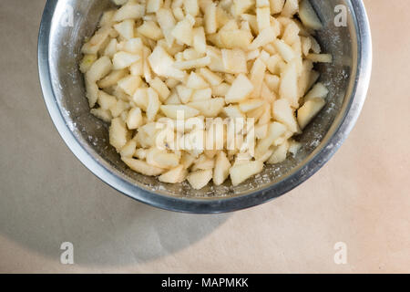 Gehackt geschälte Birnen mit Zucker in einer Metallschüssel gemischt Stockfoto