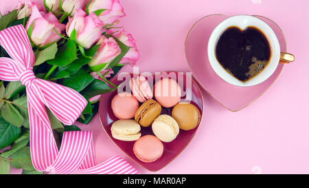 Mit Muttertag Kaffee und macarons mit Rosen Geschenk Overhead auf rosa Holz Tisch Hintergrund. Stockfoto