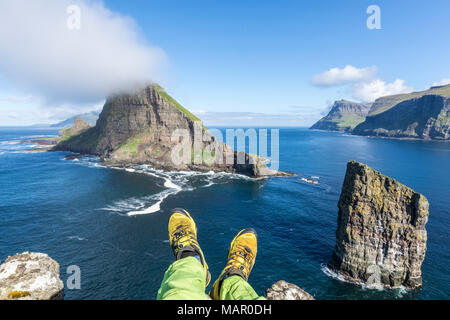 Man legt sich auf Felsen über dem Meer Stapel von Drangarnir und Tindholmur Islet, Vagar Island, Färöer, Dänemark, Europa Stockfoto