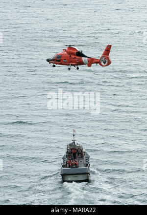 Einem MH-65 Dolphin helicopter Crew von Coast Guard Air Station Humboldt Bay schwebt über ein 47-Fuß-Motor Rettungsboot Crew während der Ausbildung in Eureka, Kalifornien, 7. März 2018. Coast Guard helicopter Besatzungen routinemäßig Training mit kleinen Boot Besatzungen ihre Qualifikationen zu erhalten und damit bei einem medevac-Anforderung von einem Boot oder Schiff, die Crews sind in Ihrer lebensrettende Techniken beherrschen. Stockfoto