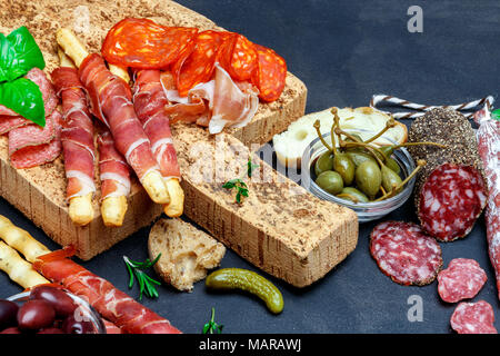 Schneidbrett mit Schinken, Salami, Brot und Oliven Stockfoto