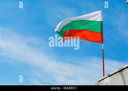 Bulgarische Flagge schwenkten gegen vibrant blue sky Stockfoto