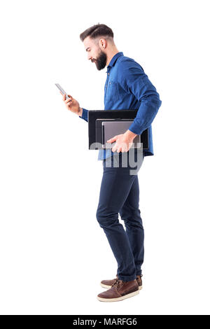 Professionelle männliche exekutive Kontrolle Telefon, Tablet-PC und Laptop unter dem Arm. Von der Seite. Voller Körper auf weißem Hintergrund. Stockfoto