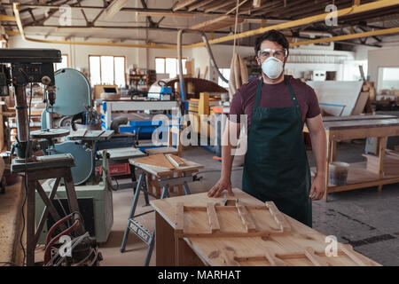 Junge woodworker in schützende Arbeitskleidung stehen in seinem Studio Stockfoto