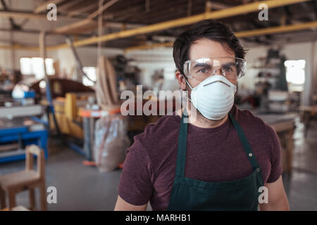 Junge woodworker allein in seiner Werkstatt mit Schutzkleidung Stockfoto