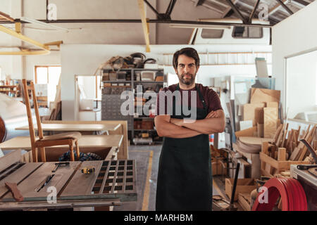 Handwerker stehen durch eine Bank sah in seiner Holzwerkstatt Stockfoto