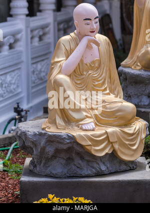 Hacienda Heights, CA, USA - 23. März 2018: Nahaufnahme von Golden drapiert Rahula mit Sack in Arhat Garten bei Hsi Lai buddhistischer Tempel. Weiße und graue Surr Stockfoto