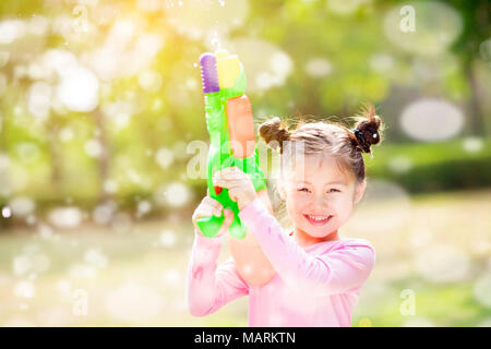 Glückliche kleine Mädchen, Wasserkanonen im Park Stockfoto
