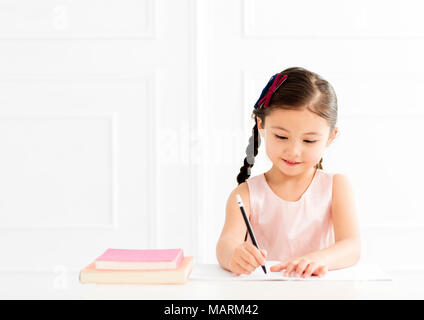 Kleines Mädchen mit Buch schreiben zu Notebook zu Hause Stockfoto