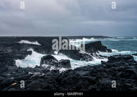 Robuste isländischen Küste mit großen Wellen schlagen die schwarzen Felsen an bewölkten Abend in South West Island. Stockfoto