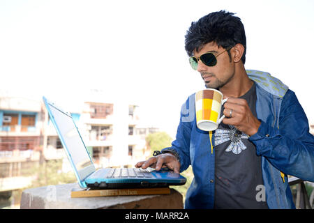 Junger Mann am Laptop zu Hause arbeiten Stockfoto