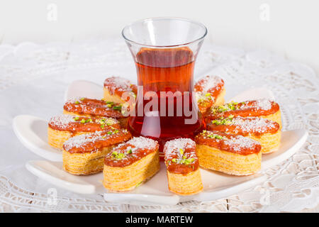 Licht knackigem Blätterteig Layered Gebäck garniert mit Pistazien & Kokos Flocken und Tasse Tee Beliebte persische Spezialitäten im Iran aufgerufen oder Zaboon Zaban Stockfoto