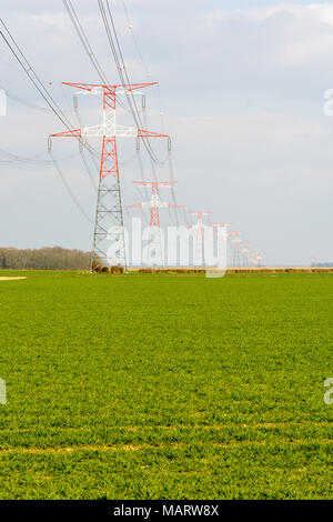 Die Oberleitung durch rote und weiße Sendemasten über die französische Landschaft unterstützt, mit einem Getreidefeld im Vordergrund. Stockfoto