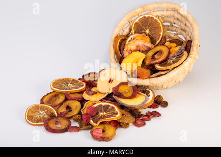 Nahaufnahme von organischen Rohstoffen Sonne getrocknete Früchte Gießen aus Warenkorb Mix aus Orangen, Pflaumen, Erdbeeren, goldenen Beeren und Pfirsich isoliert auf weißem Hintergrund Stockfoto