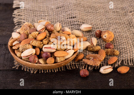 In der Nähe von Pile organischer Rohstoffe Muttern Mix von Pistazien, Mandeln, Walnüsse, getrocknete Maulbeeren, getrocknete Feigen und Haselnüssen auf Holzplatte und Tabelle Backgro Stockfoto