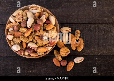 Blick von oben auf die organische Rohe Nüsse Mix von Pistazien, Mandeln, Walnüsse, getrocknete Maulbeeren, getrocknete Feigen und Haselnüssen auf Holzplatte und Tabelle Hintergrund, Hea Stockfoto