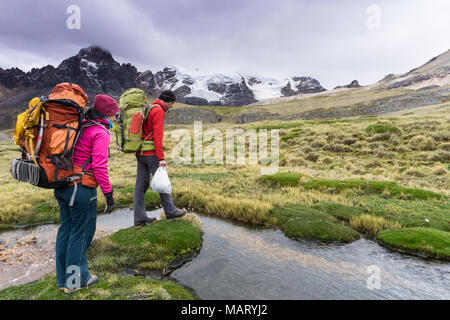 Männliche Bergsteiger und weiblichen Partner machen Sie sich bereit, ein kleiner Bach in der Cordillera Blanca in Peru zu Kreuz Stockfoto