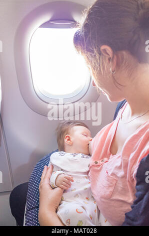 Mutter stillen ein zwei Monate altes Baby im Flugzeug, Großbritannien Stockfoto