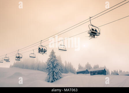 Skifahrer und Snowboarder unterwegs auf einem Sessellift in Morzine Skigebiet in Frankreich. Split getönten Farben Behandlung. Stockfoto