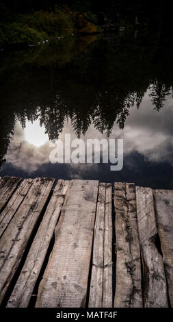 Die Reflexion der Sonne im Klaren, noch Wasser von Fichte See (South Chilcotin Mountains Park) als aus dem Dock gesehen. (BC, Kanada) Stockfoto