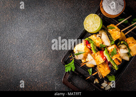 Vegane Ernährung Essen, gegrillten Käse und Gemüse Kebab, im indischen Stil Paneer Tikka, mit weißer Soße und Kalk, auf dunklen konkreten Hintergrund, kopieren, um Platz zu Stockfoto