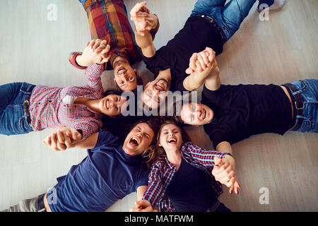 Ansicht von oben. Eine Gruppe von Freunden Lachen auf dem Boden liegt. Stockfoto