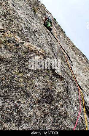 Kletterer in hellen Farben gekleidet auf einem steilen Granit Klettersteig in den Alpen Stockfoto