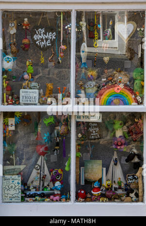 Eine eklektische Mischung aus Spielzeug und verschiedene interessante Elemente im Fenster eines kleinen Küsten Cottage an der Küste von Cornwall. Alte Neugier shop Fenster aufzurufen. Stockfoto