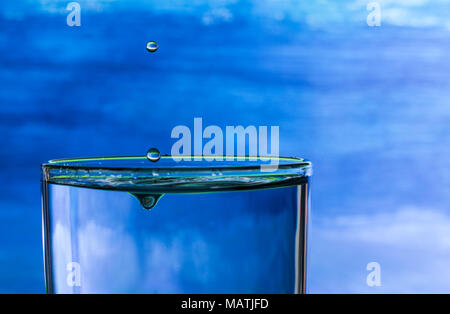 Wassertropfen spritzen in einem Glas Trinkwasser Stockfoto
