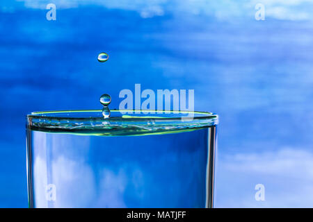Wassertropfen spritzen in einem Glas Trinkwasser Stockfoto