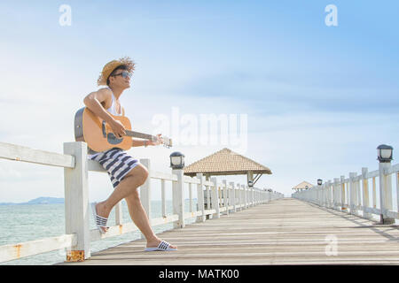 Junge Menschen spielen eine akustische Gitarre am Strand Stockfoto
