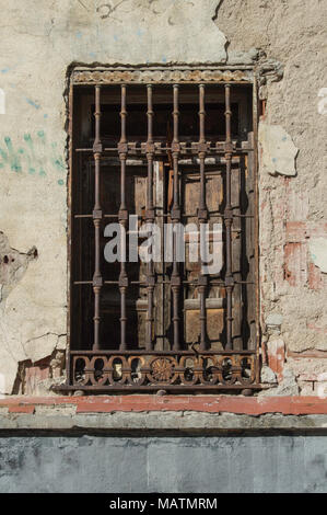 Alte Fenster mit Fensterläden aus Holz und rostigen Zaun auf eine abgeplatzte Wand in einem Gebäude in Madrid. Spanien Stockfoto