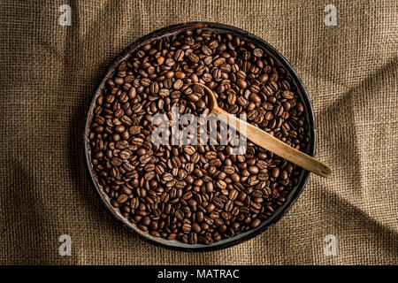 Kaffeebohne in Schale mit Löffel aus Holz Stockfoto