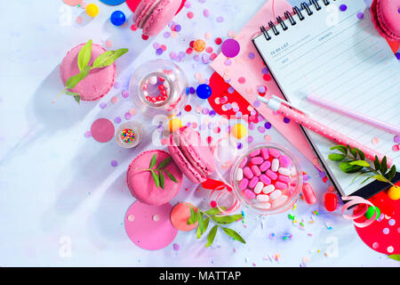 Notepad mit leeren Seiten öffnen sich in einem Organisation einer Party Konzept mit Konfetti, rosa Macarons, Bonbons und Streuseln. Kreative Event To-do-Liste flach Stockfoto