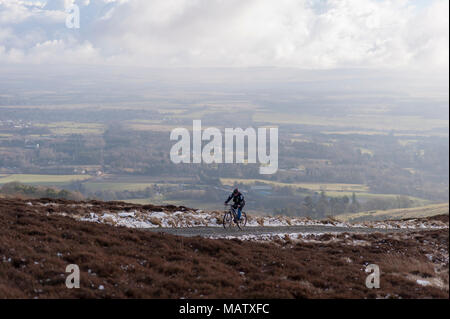 Ein Mann uphill Radfahren auf einem Pfad in den verschneiten Pentlands Hügeln in der Nähe von Edimburgh Stockfoto