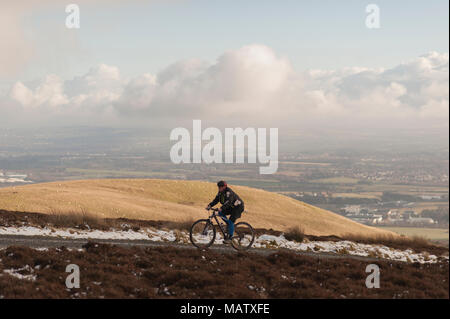 Ein Mann uphill Radfahren auf einem Pfad in den verschneiten Pentlands Hügeln in der Nähe von Edimburgh Stockfoto