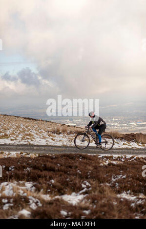 Ein Mann uphill Radfahren auf einem Pfad in den verschneiten Pentlands Hügeln in der Nähe von Edimburgh Stockfoto