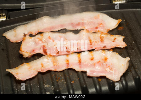 Bauchspeck, unsmoked EU Speck von einem Supermarkt gebraten auf einem George Foreman Grill Fett reduzieren mit dem natürlichem Fett des Specks. Großbritannien Stockfoto